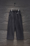 Dark gray washed wide-leg sweatpants hanging on a clear plastic hanger against a dark textured stone wall. The pants feature an elastic waistband, side pockets, and a small white 'nexus' logo on the upper left hip.chrome hearts men’s jogger 