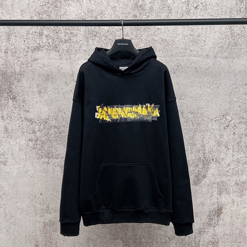 A black Balenciaga hoodie hanging on a black hanger against a textured gray concrete wall. The hoodie features a distressed yellow and white 'SAVANGELISTA' graphic across the chest.